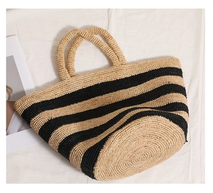 Close-up of black and yellow striped raffia tote bag with handwoven straw texture