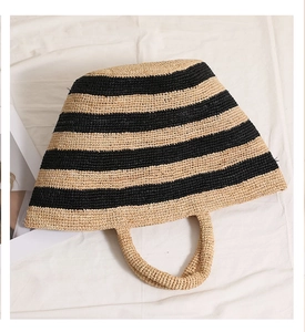 Detail of raffia tote bag showing woven straw texture and black striped pattern