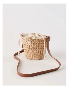 Détail du sac seau en paille tressée avec cordon de serrage et bandoulière en cuir