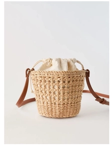 Détail d'un sac seau en paille avec texture en maille ajourée et pochette intérieure à cordon interne