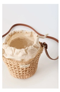 Détail du sac seau tressé avec doublure en toile et bandoulière en cuir marron