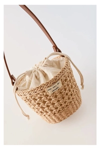 Détail du sac seau en paille tressée avec doublure en toile et étiquette logo