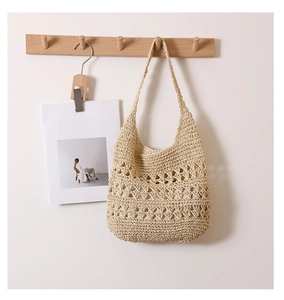 Detailed close-up of hollow geometric crochet pattern on beige straw tote bag