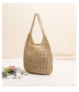Detail of hollow-out handwoven straw tote bag with natural fiber texture on white fabric