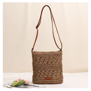 Close-up of hand-woven straw crossbody bag with retro hollow pattern and leather strap