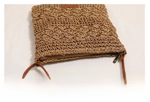 Detailed macro view of woven straw texture and smooth brown zipper closure on crossbody bag