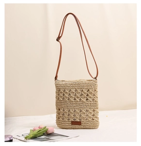 Detailed macro view of woven straw crossbody bag featuring natural hollow lattice patterns