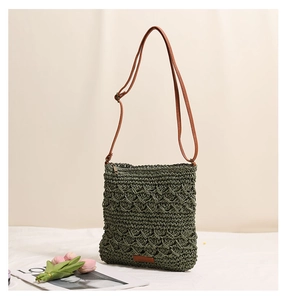 Detail of green straw woven crossbody bag featuring diamond mesh texture and leather strap