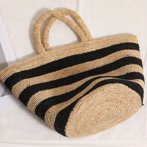 Large striped raffia tote bag with round handles and woven texture for beach vacation