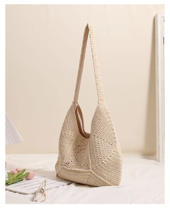 Detailed close-up of intricate hand-woven hollow flower patterns on a beige crochet shoulder bag