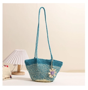 Detail of gradient blue woven straw bag with beige floral ornament and long strap