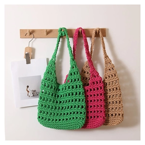 Detail of hand-woven hollow mesh bags in green, fuchsia, and khaki on a wooden hanger
