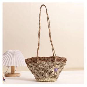 Detail of handwoven straw tote bag with brown and cream stripes and floral pendant