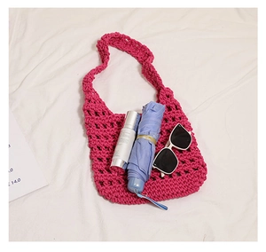 Detail of fuchsia crochet bag showing large capacity with umbrella and sunglasses