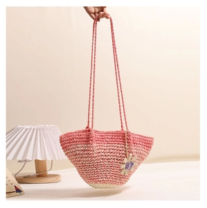 Close-up of handmade pink gradient woven straw bag with a delicate purple flower charm