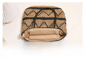 Detail view of large straw tote bag with black geometric pattern and smooth zipper closure