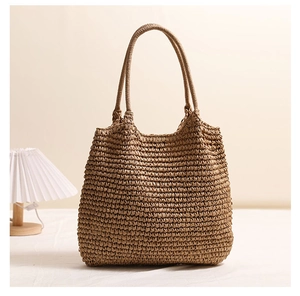 Detailed close-up of large straw tote bag texture and handles on a white linen surface