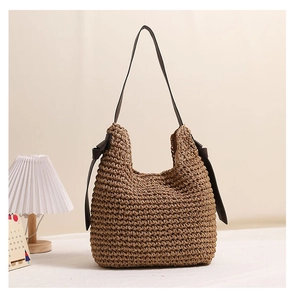 Dettaglio della borsa in paglia intrecciata con texture e fiocchi in pelle marrone