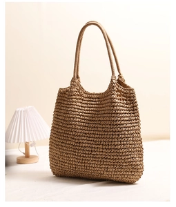 Detail of hand-woven straw tote bag in a cozy home setting with warm lighting