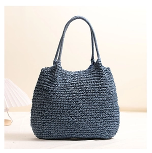 Detail of deep blue woven straw tote bag texture and durable cylindrical shoulder straps