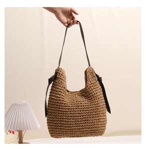 Dettaglio della borsa a tracolla in paglia con fiocchi decorativi in pelle e tracolla lunga