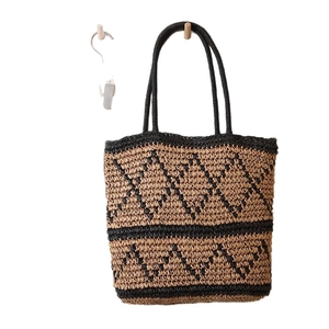 Straw tote bag with black chevron pattern and long handles for beach vacations