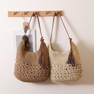 Hollow straw shoulder bag with tassels and leather straps for summer beach vacations