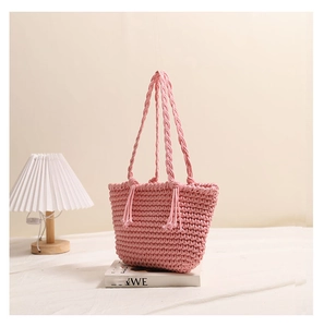 Close-up of pink woven cotton bag texture with fringe tassel and hand-braided strap