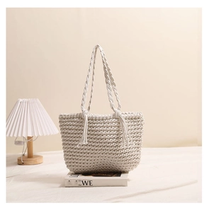 Detail of hand-woven off-white cotton tote bag with tassel accents and braided straps