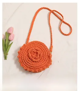 Detail of round orange hand-woven crochet bag with 3D floral accents on cotton fabric