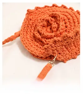 Detailed macro view of orange hand-knitted floral bag with metallic golden lobster clasp