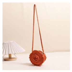 Detail of a handmade orange round crochet bag with a 3D floral rose and woven strap