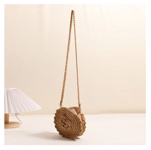 Close-up of hand-woven round straw bag with 3D floral accents and wavy edge detail