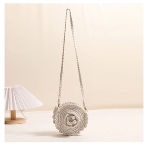 Close-up of handmade round crochet crossbody bag with 3D floral details and metal buckle
