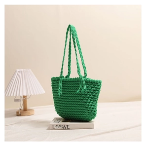 Detail of green handmade crochet woven tote bag with fringe tassels and knot handles