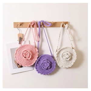 Detailed view of handmade woven cotton bags with 3D roses hanging on wooden wall hooks