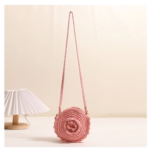 Detail of a round pink hand-woven rose crochet shoulder bag hanging by a pleated lamp