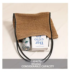 Dettaglio della grande capacità della borsa in paglia con libri e un ombrello inclusi