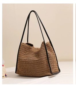 Dettaglio della borsa tote in paglia intrecciata con spalline in pelle nera e trama fine