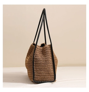 Dettaglio della borsa tote in paglia intrecciata con finiture in pelle nera da spiaggia