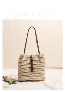 Close-up of beige crochet tote bag with wooden bead buckle and long brown leather tassels