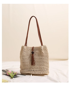 Detail of beige hollow woven shoulder bag with brown tassels and wooden beads decor
