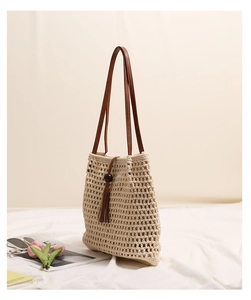 Detail of cream woven cotton tote with brown leather straps and wooden bead tassels
