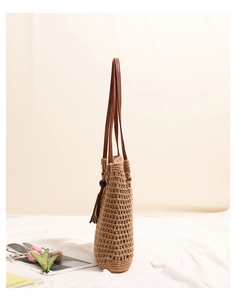 Detail of woven straw shoulder bag with wooden bead tassel and brown leather strap