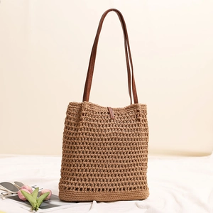 Handwoven straw tote bag in light brown with dark leather straps for beach vacations