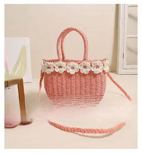 Detailed macro view of pink straw handbag with white crochet floral patterns and woven straps