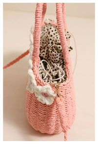 Close-up of pink woven straw bag with white 3D flowers and polka dot drawstring lining