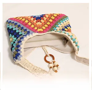 Close-up of smooth zipper closure and tassel charm on a colorful crochet shoulder bag