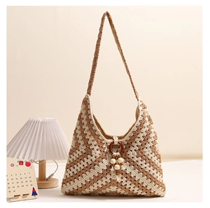 Detail of bohemian knit tote bag showing wooden ring handle and tassel accents
