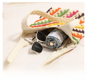 Macro view of colorful striped straw bag showing spacious interior with sunglasses and umbrella